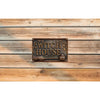 A vintage metal sign with the words WITCH HOUSE and a broom and cauldron design mounted on weathered wooden planks.