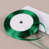 A spool of green satin ribbon is shown on a white surface.