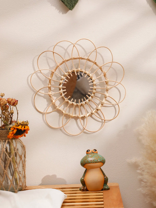 Hand woven rattan decorative wall mirror with a sunburst design mounted on a light wall.