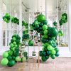 A large arrangement of sage green latex balloons in various shades of green and dark green, displayed indoors.