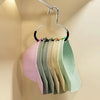 A rack of colorful circle ring hats hanging on a metal hanger against a light beige wall.