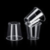 A clear plastic shot glass is shown tilted against a black background.