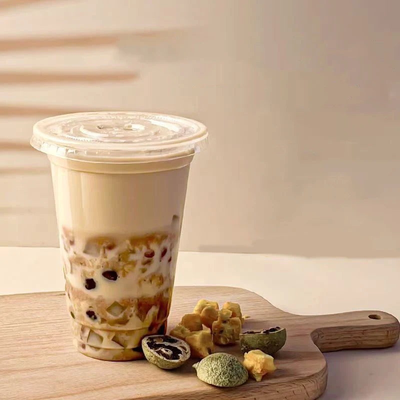 A tall plastic cup filled with a layered iced drink, resting on a wooden board.