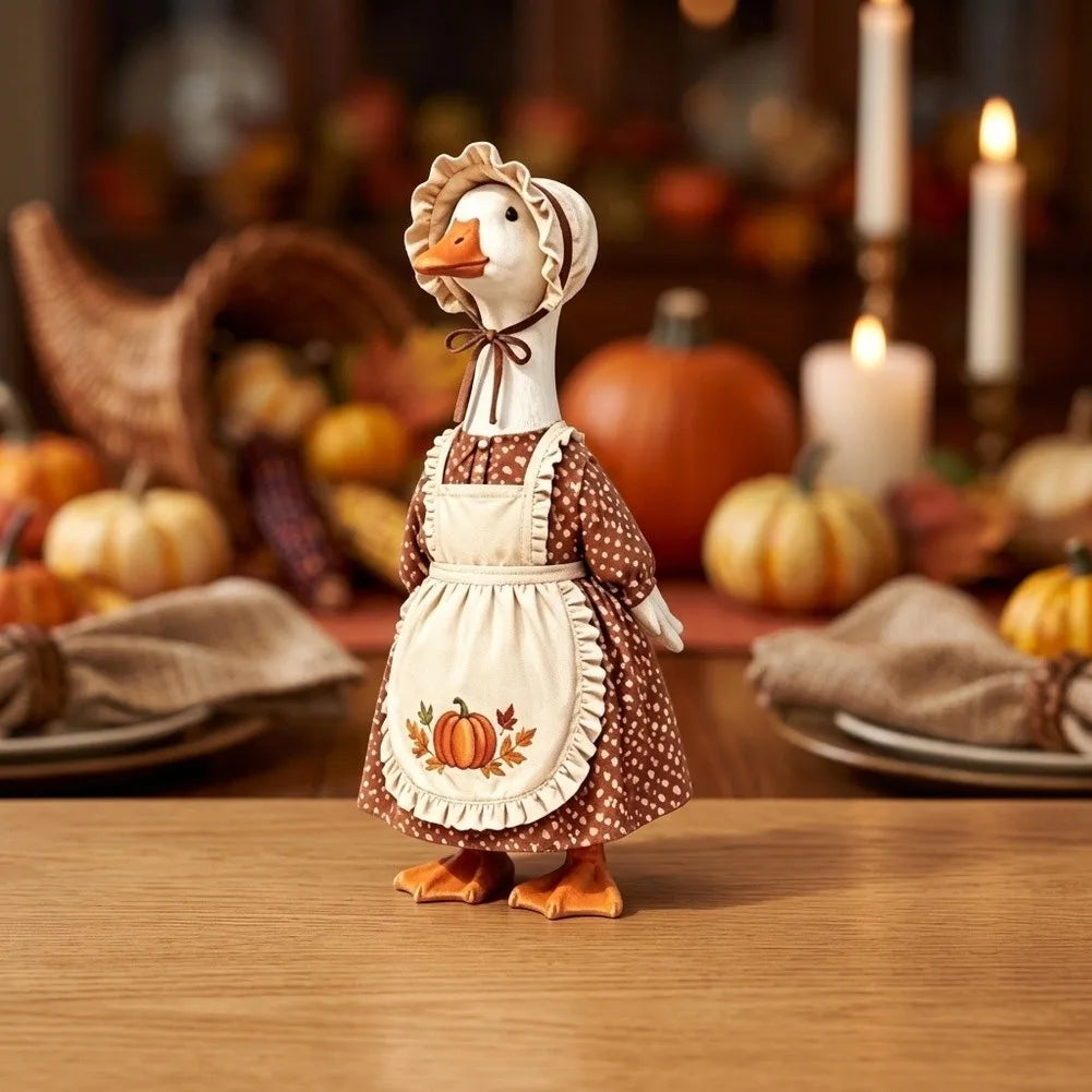 A ceramic goose figure wearing an apron and headband, displayed among autumn harvest decor.