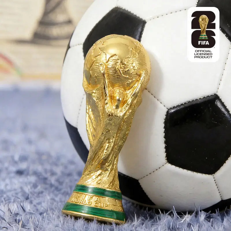 A gold FIFA World Cup trophy is placed on a black and white soccer ball.