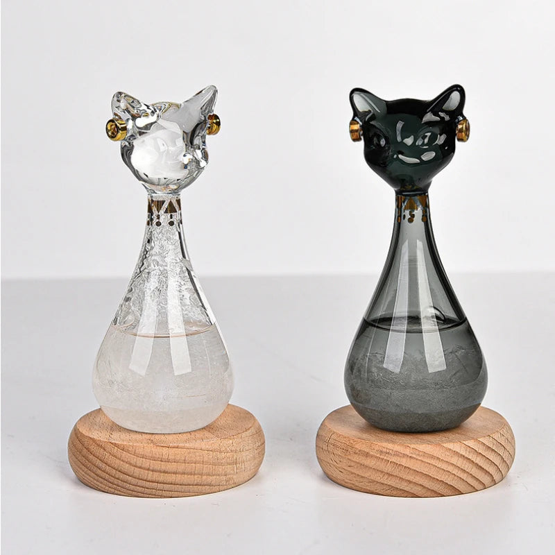 A glass bottle decoration shaped like an Egyptian cat, featuring a clear body and black details, resting on a wooden base.