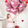 Ein junges Mädchen in einem rosa Kleid blickt auf einen Haufen rosa Herzballons über dem Kamin.