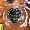 A clear plastic dessert packaging box with a black lid featuring gold confetti and the text Thank You for Celebrating 90.