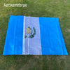 A blue and white flag display featuring the Guatemala National Flag design on a green lawn.