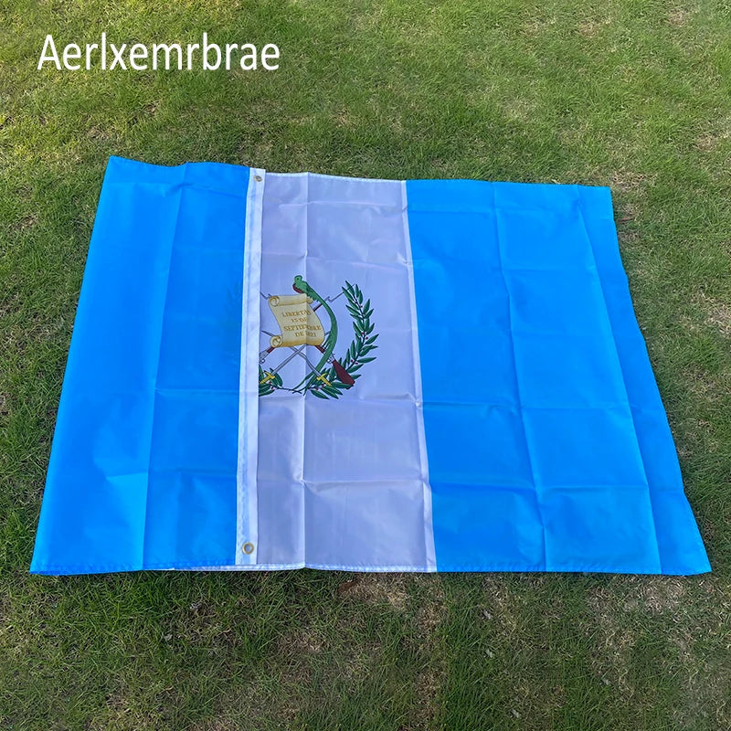 A blue and white flag display featuring the Guatemala National Flag design on a green lawn.