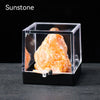 A rough, translucent orange-yellow gemstone specimen is displayed inside a clear acrylic box.