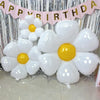 A bouquet of white and yellow foil balloons shaped like daisies is displayed against a silver backdrop.