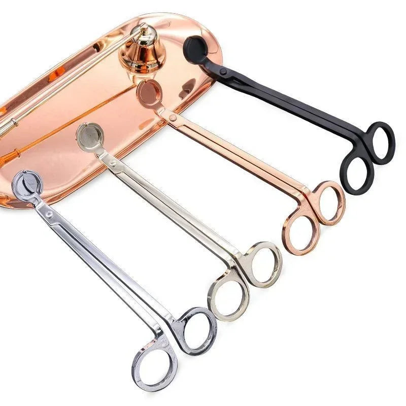 A pair of stainless steel candle wick trimmer scissors with a rose gold handle and black grip.