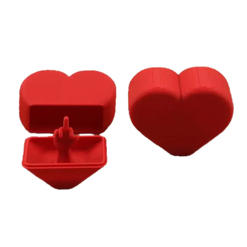 A red heart-shaped novelty desk decor item with a lid open, showing a small object inside.