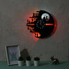 A black vinyl record shaped wall lamp with a glowing face and clock design mounted on a gray wall.