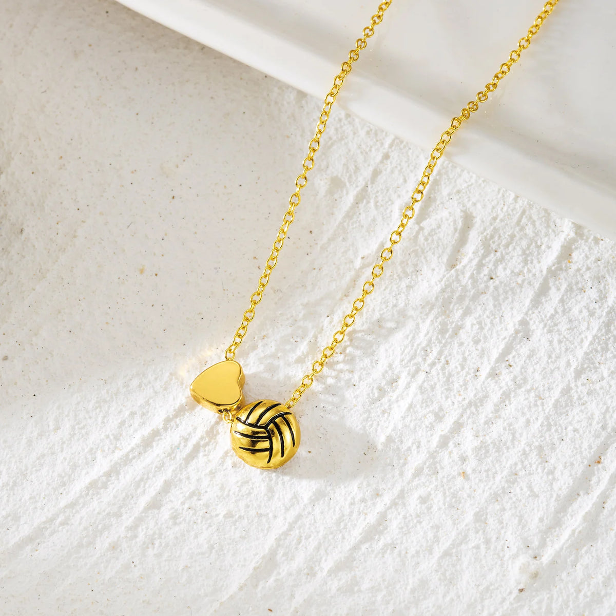 Gold heart pendant necklace featuring a woven basketball charm on a white textured background.