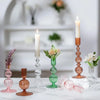 A set of three groovy wavy glass taper candle holders in pink and amber tones displayed on a white surface.