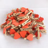 A pile of small, heart-shaped wooden photo clips in orange and natural wood tones.