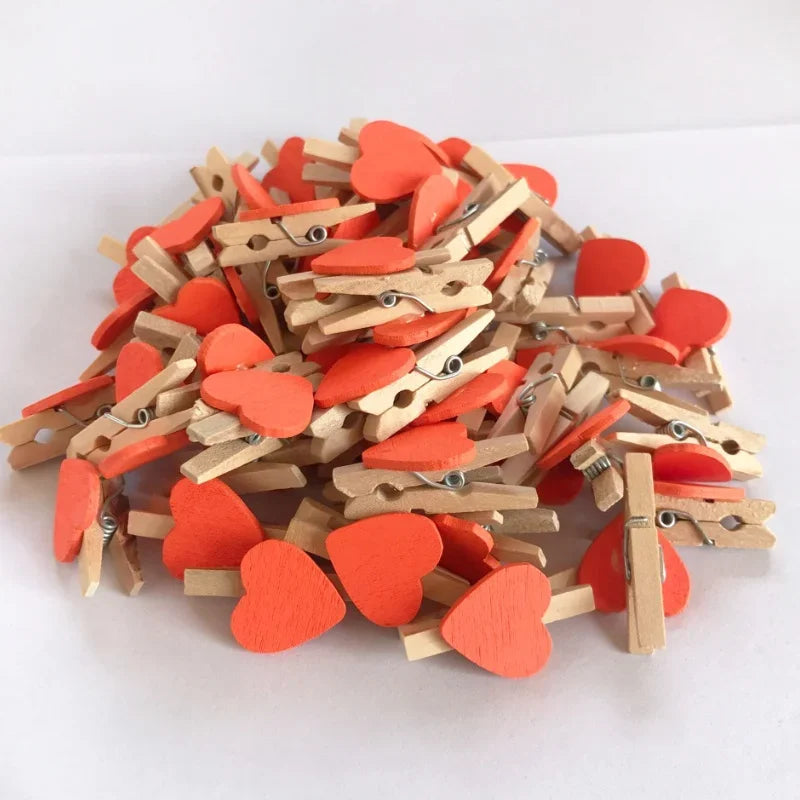 A pile of small, heart-shaped wooden photo clips in orange and natural wood tones.