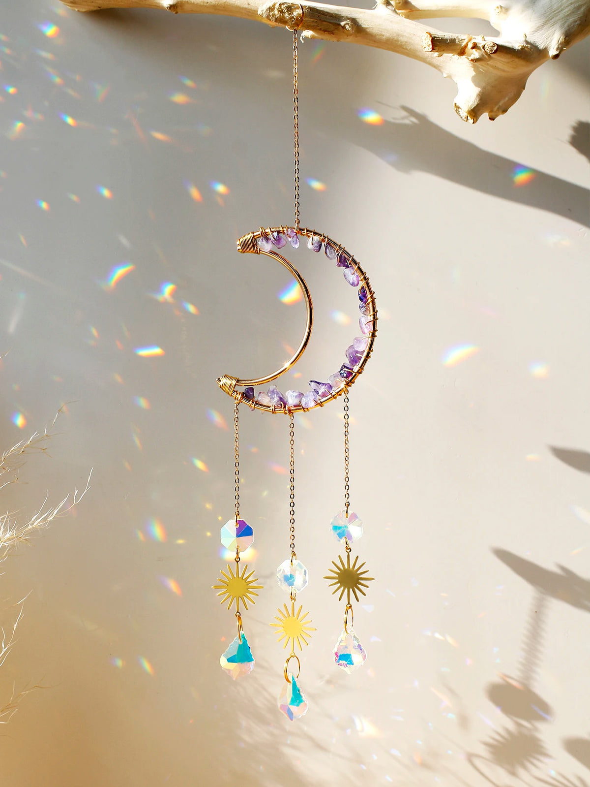 A handcrafted moon crystal suncatcher featuring a gold pendant and purple crystals hanging against a bright background.