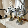 A white 3D gamepad controller is displayed next to a metallic storage organizer for robotic hands.