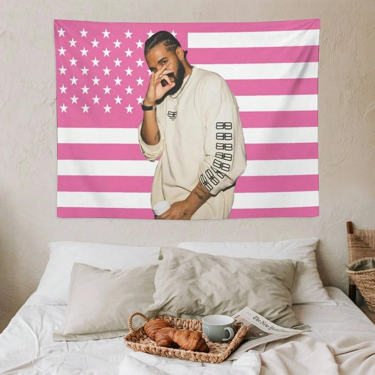 Un homme en chemise claire pose devant une tapisserie de drapeau américain rayé rose et blanc.