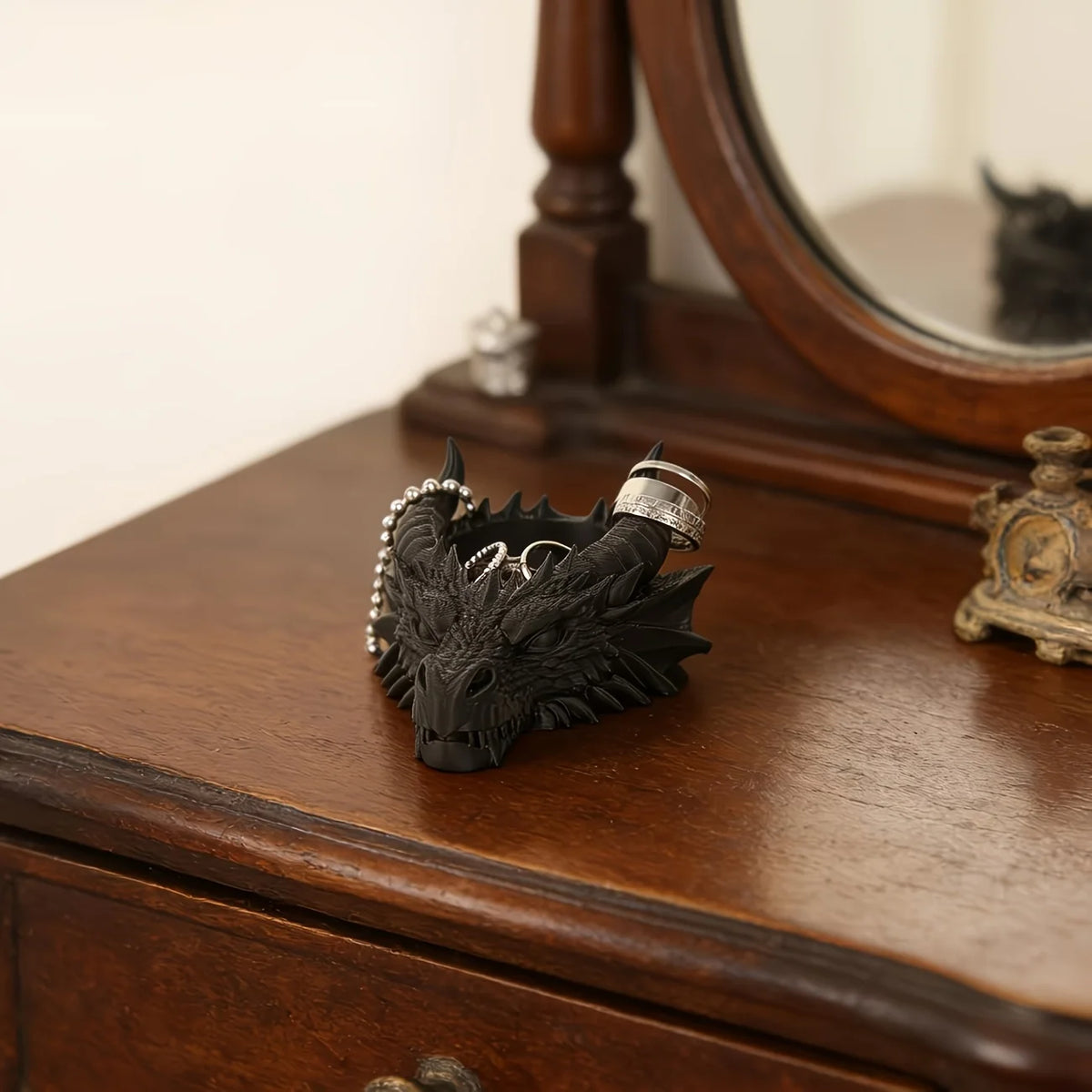 Tête de dragon noire pour bureau décor, avec des anneaux et des dents en argent, sur une surface en bois sombre.