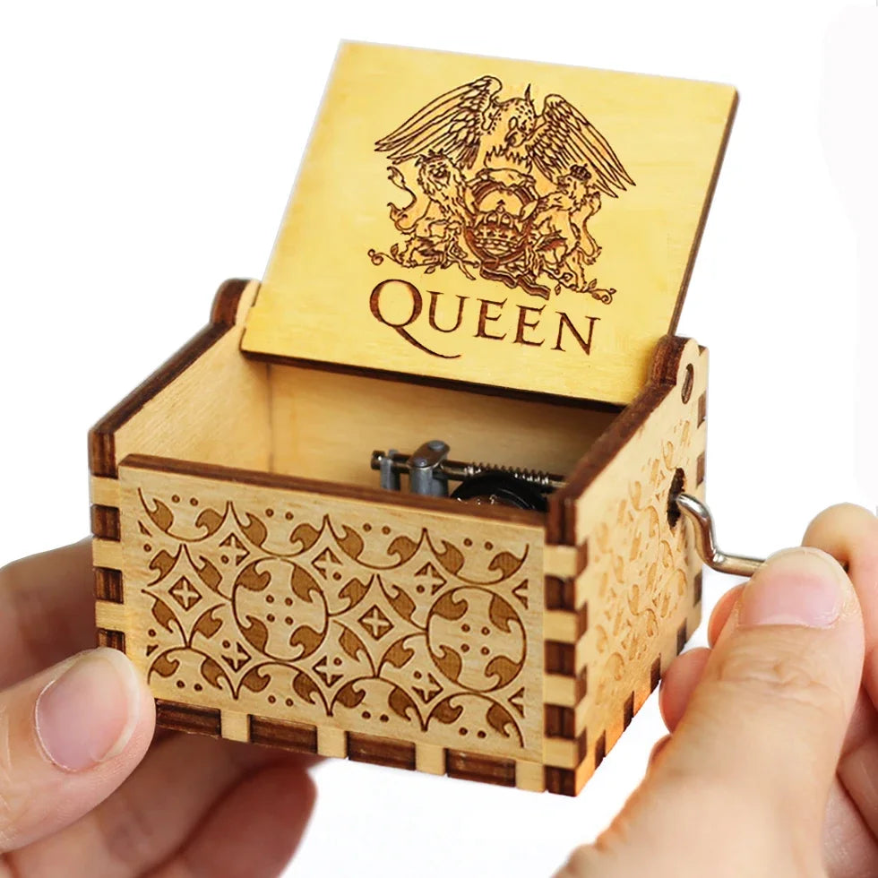 A carved wooden music box with a lid featuring an eagle design is held in a hand.