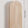 Jarrón de pared arqueado de madera clara con estrías verticales montado en una pared blanca.