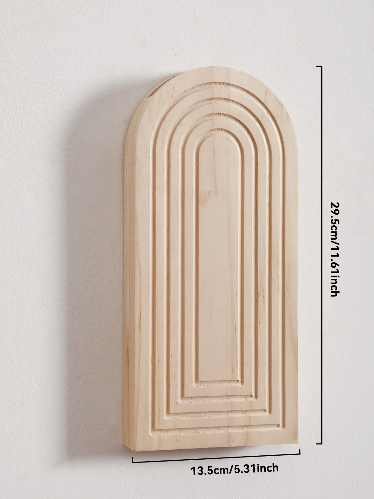Jarrón de pared arqueado de madera clara con estrías verticales montado en una pared blanca.