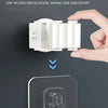 A hand is installing a wall-mounted mop and broom holder onto a dark surface.