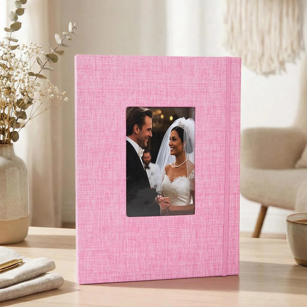 A pink linen photo album with a black and white wedding photo inside, resting on a wooden surface.