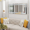 A rectangular silver crystal rhinestone wall mirror with a sparkling frame mounted on a white wall above a light-colored sofa