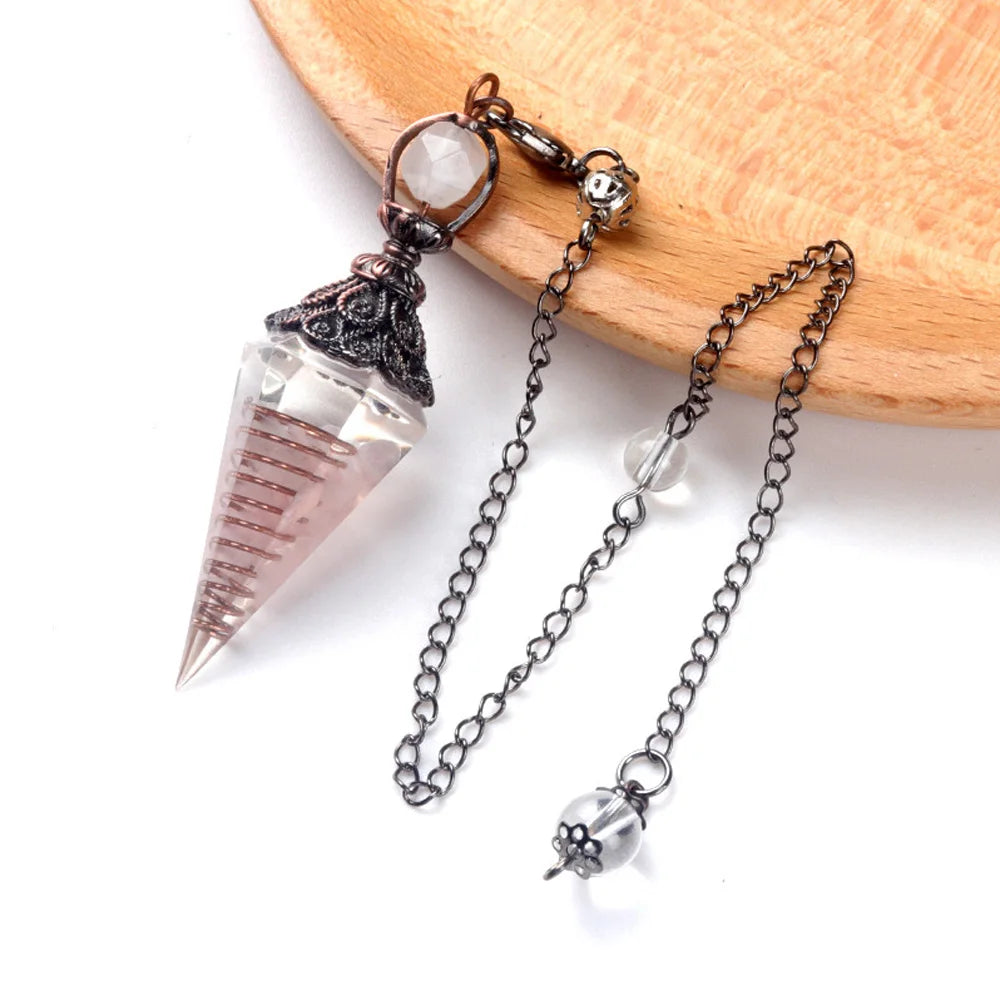 A set of natural crystal pendulum necklaces featuring clear quartz and silver accents displayed on a wooden surface.