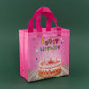 A pink reusable happy birthday gift bag with pink ribbon and a birthday cake design.