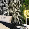 A close-up of a black and white zebra print wallpaper featuring a large leaf and a glowing star accent.