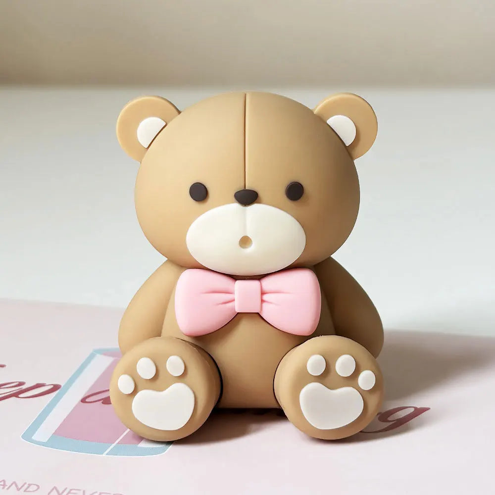 A light brown teddy bear figurine with pink accents and paw prints sitting on a white surface.