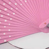 A pink wooden hand fan with pleated ribs and white polka dots shown in a close-up angle.