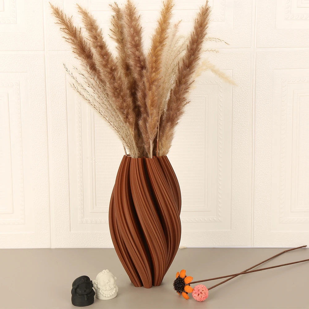 A tall arrangement of dried grasses in a textured terracotta vase on a light surface.