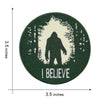 Dark green circular embroidered patch featuring a silhouette of Bigfoot within a tree outline and the word I BELIEVE.