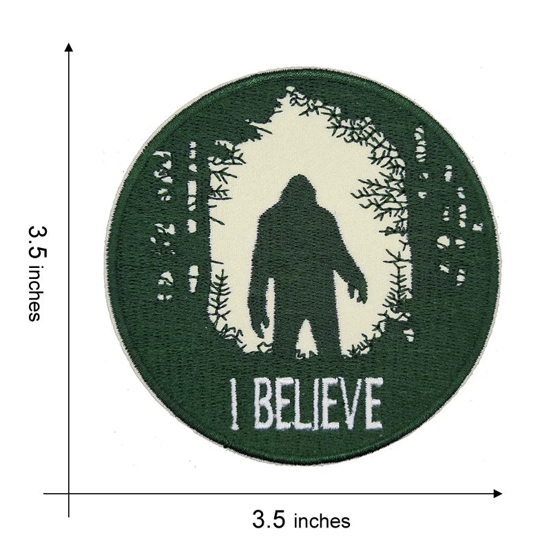 Dark green circular embroidered patch featuring a silhouette of Bigfoot within a tree outline and the word I BELIEVE.