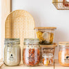 Glass jars filled with rice, macaroni, and oats displayed on a wooden surface.