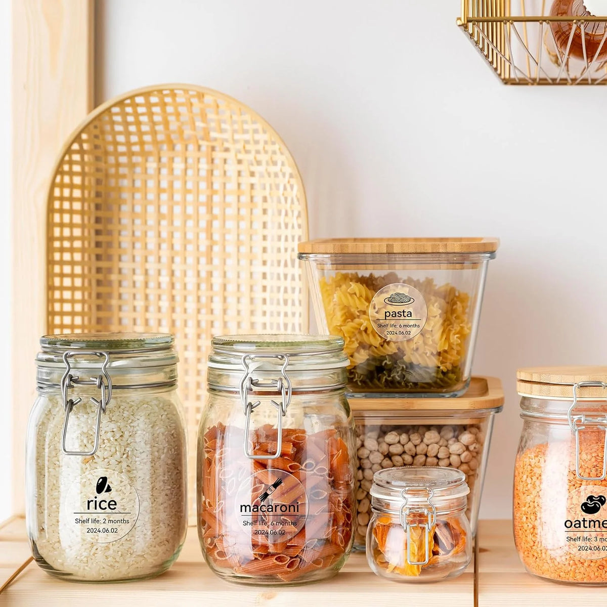 Glass jars filled with rice, macaroni, and oats displayed on a wooden surface.