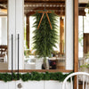 Artificial Christmas teardrop swag made of green Norfolk pine needles hanging in a wooden frame.