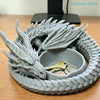 A gray dragon design decorative tray holding a gold key and silver coins.