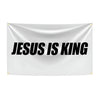 A white fabric banner with the black text JESUS IS KING displayed on a flag.