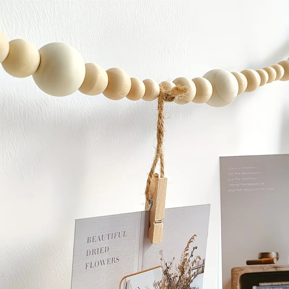 A beige beaded photo display garland with natural twine and wooden clips hanging on a white wall.
