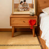A wooden nightstand with a framed photo of two people and a red heart ornament on the front.