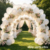 A floral archway made of matte white latex balloons decorated with pink roses and greenery for an event backdrop.
