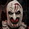 A close-up of a white horror clown mask with red paint drips and dark features.